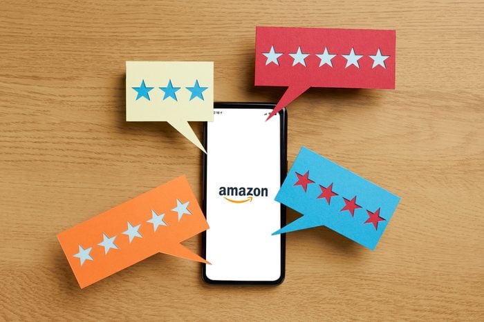 amazon app opening on a phone with speech bubbles of stars around it to represent reviews on a wood table background