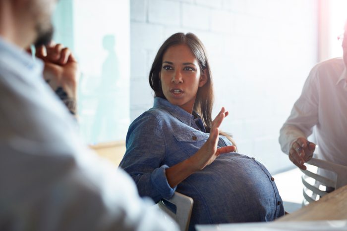 Pregnant woman explaining to co-worker