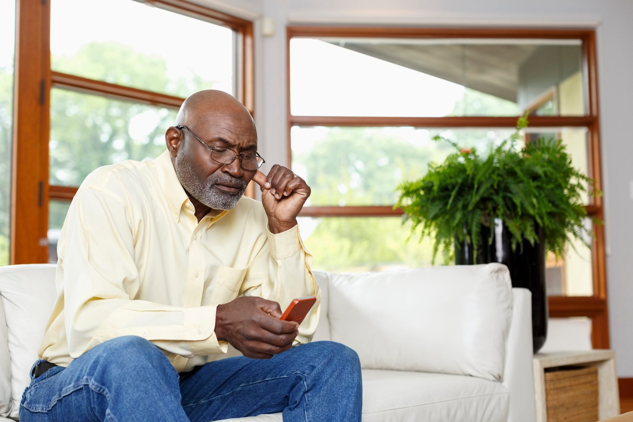 Black man texting with cell phone on sofa
