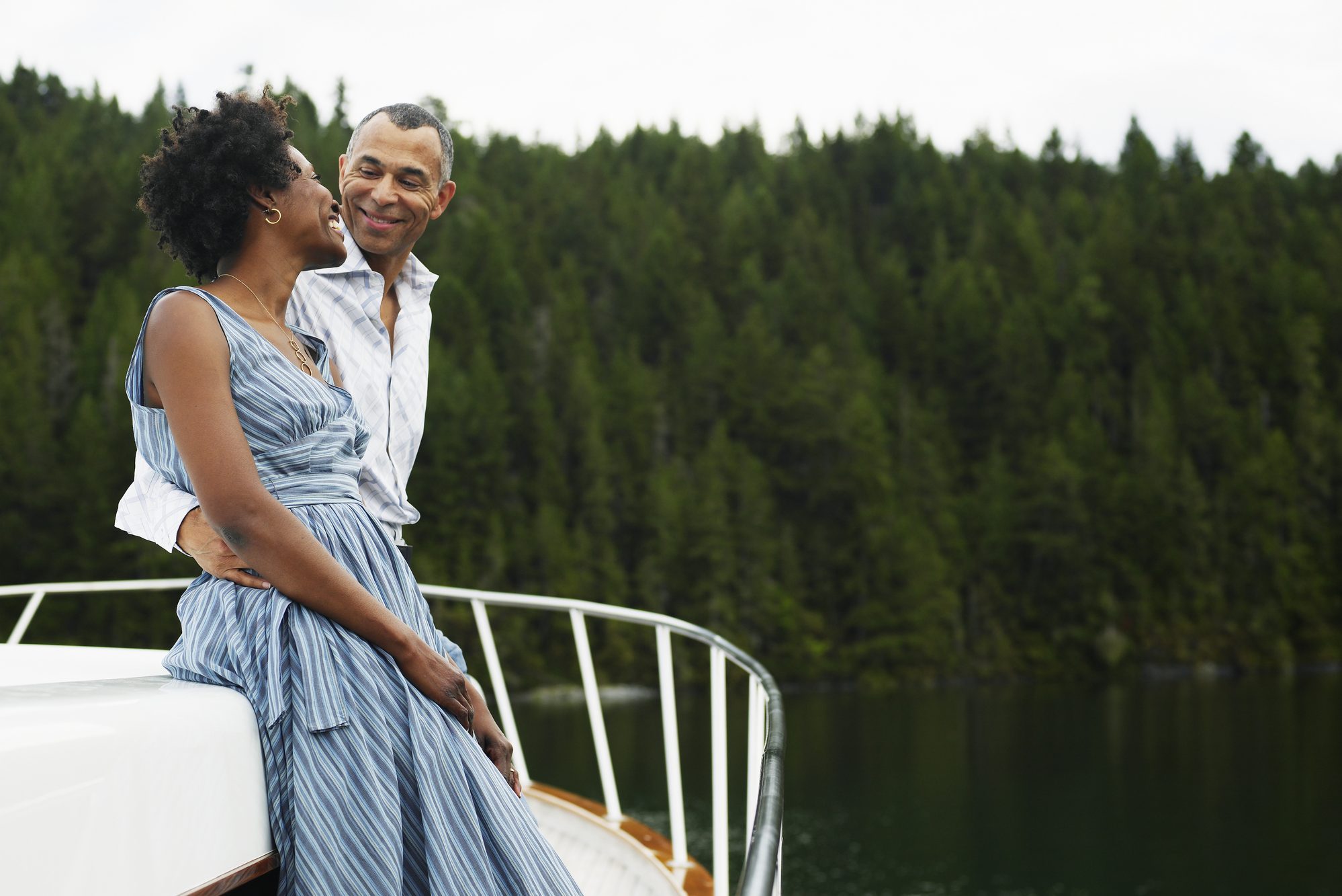 Mature man with arm around woman on yacht, smiling