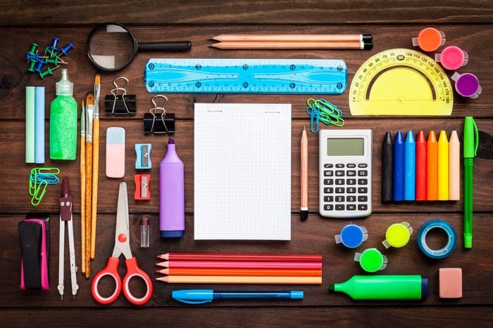 Top view of a large group of school or office supplies on wooden table