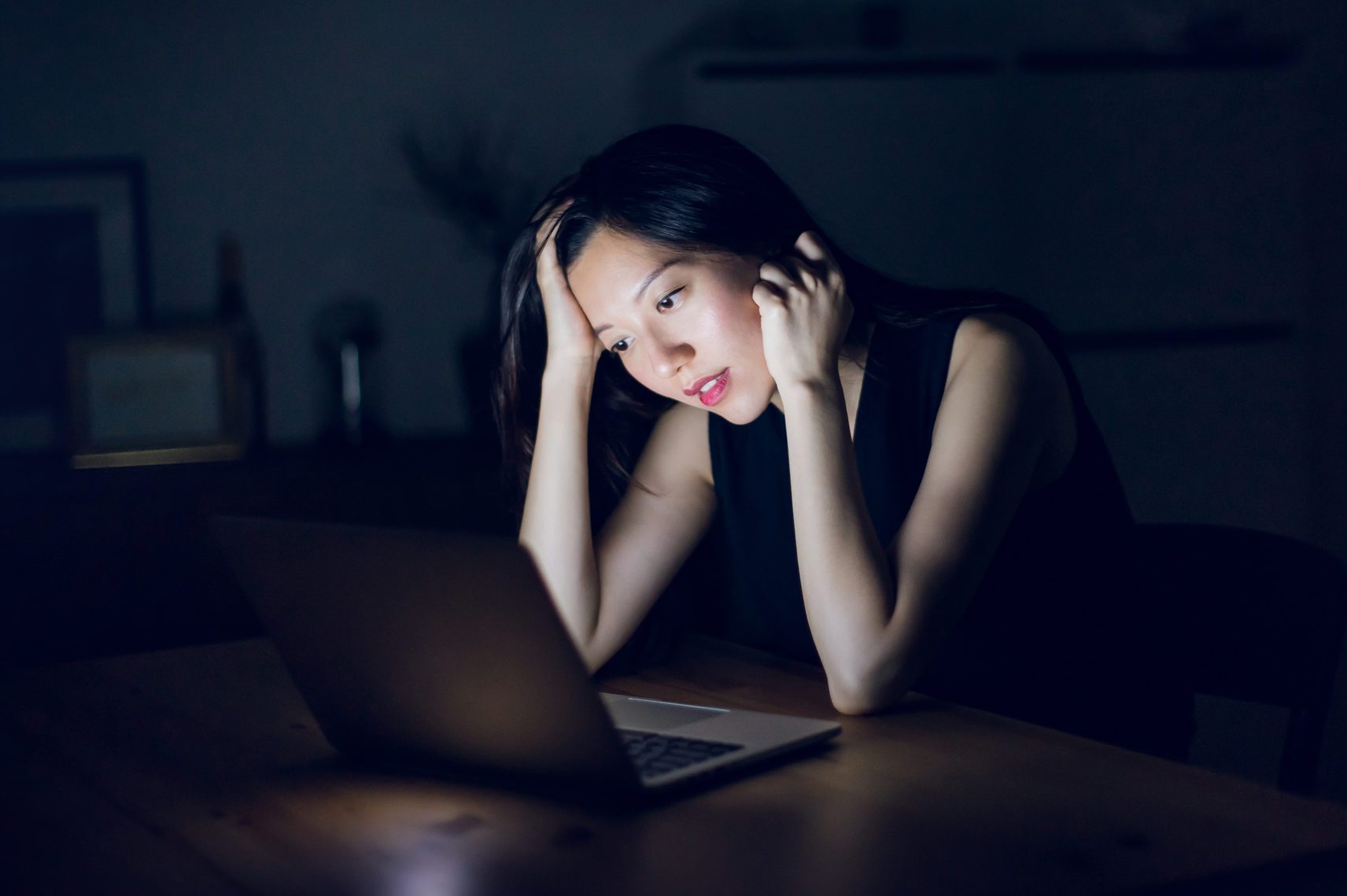 Stressed and frustrated businesswoman working on laptop till late at work