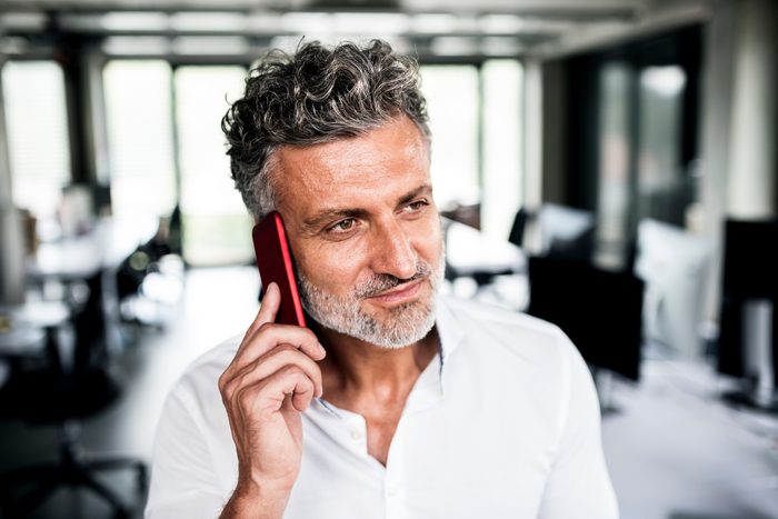 Portrait of mature businessman on cell phone in office