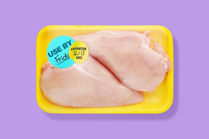 purple background with raw chicken in a yellow Styrofoam tray with two different expiration and Best Buy stickers.