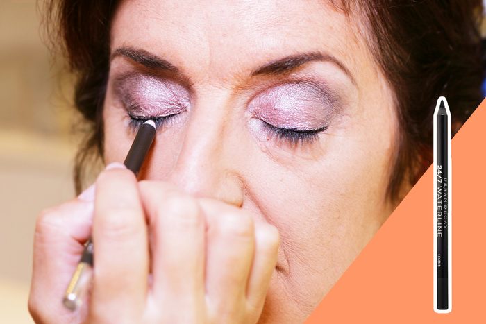 woman applying eye pencil make up