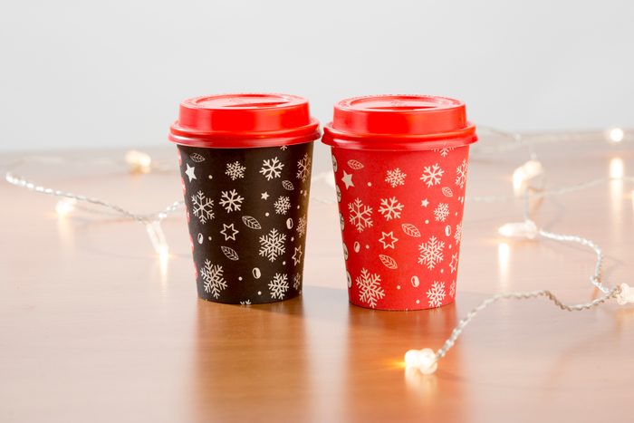 Coffee to go in red cup on black and christmas decorations