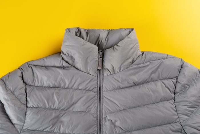 upper part of mens insulated down jacket on yellow background