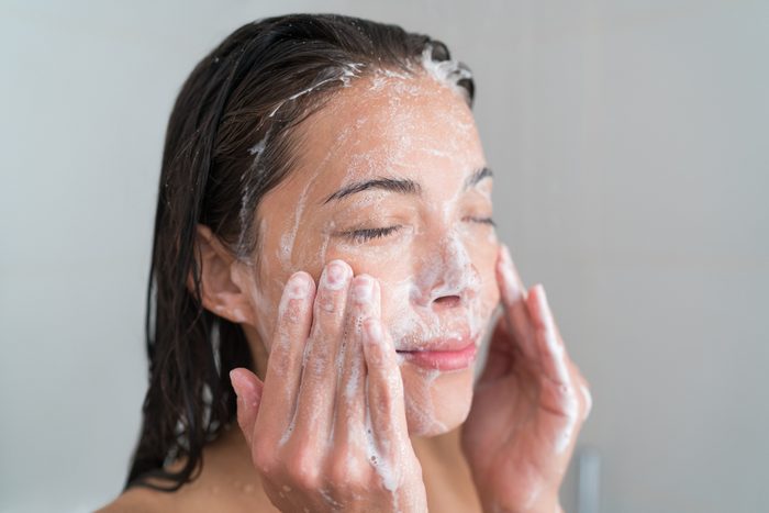Skincare woman washing face in shower