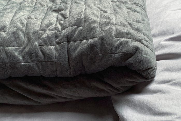 Натюрморт из серого, утяжеленного, одеяла в спальне