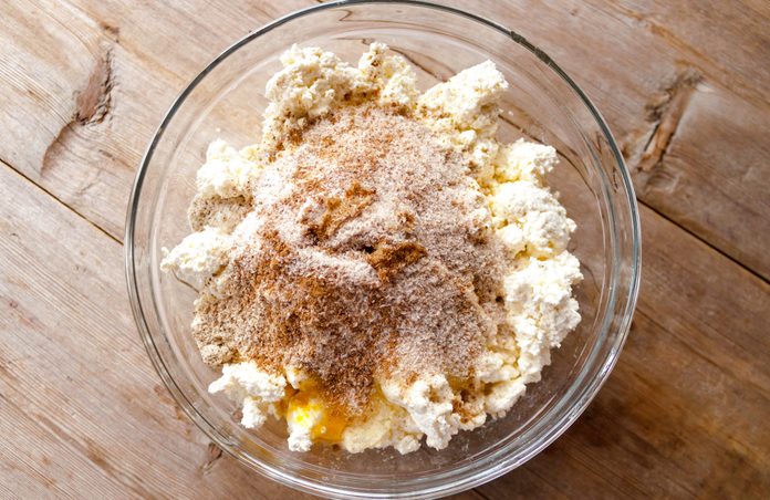 Raw mixture for making cottage cheese cakes in glass bowl on old wooden background