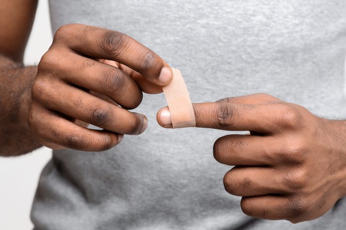 Close up of man using adhesive tape on injured finger