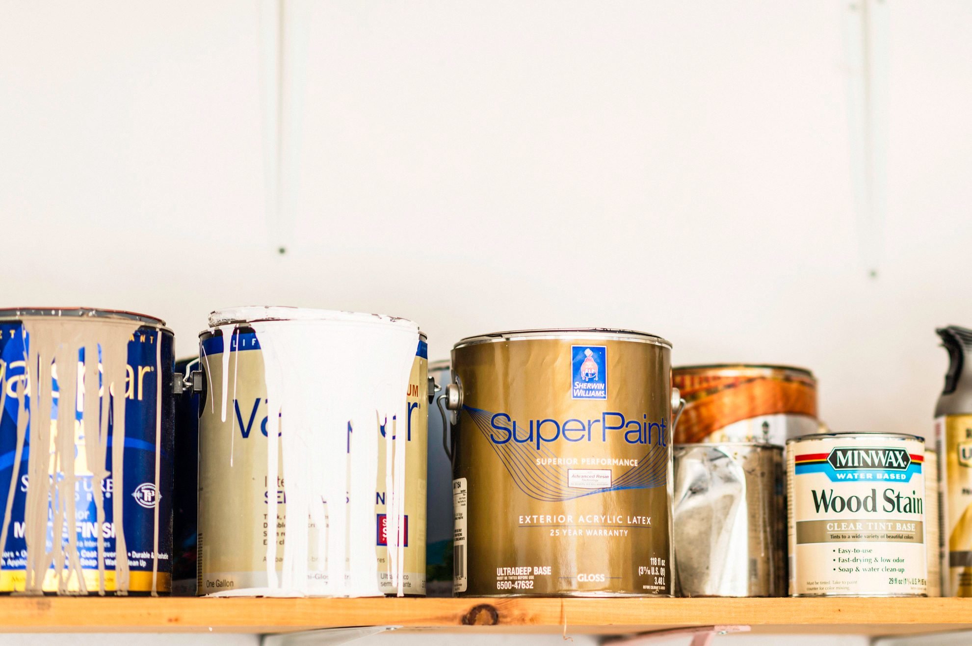 Assorted cans of paint, spray paint and wood stain.