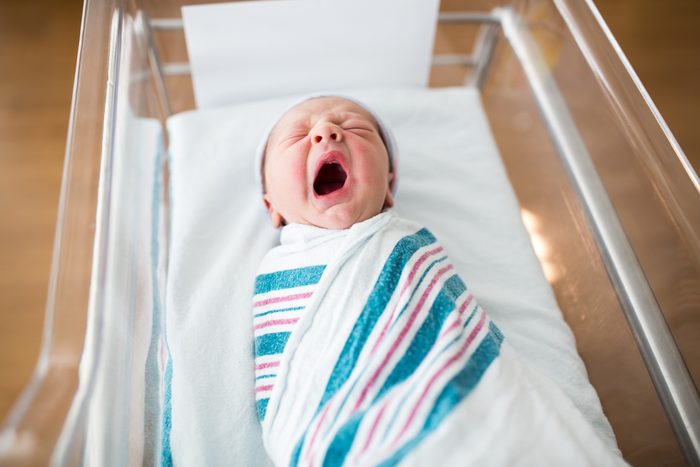 Newborn Infant Yawning in Crib