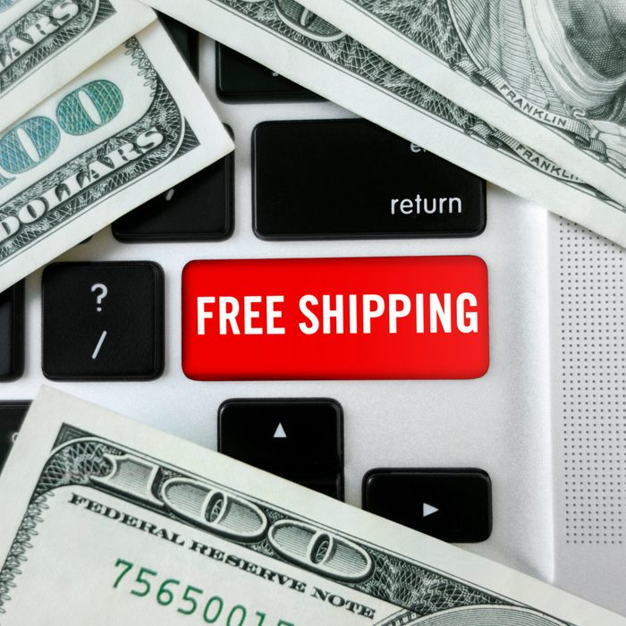 close up "Free shipping" button on a laptop keyboard with 100 dollar bills