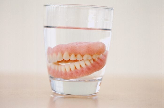 Close-up of a set of dentures in a glass of water