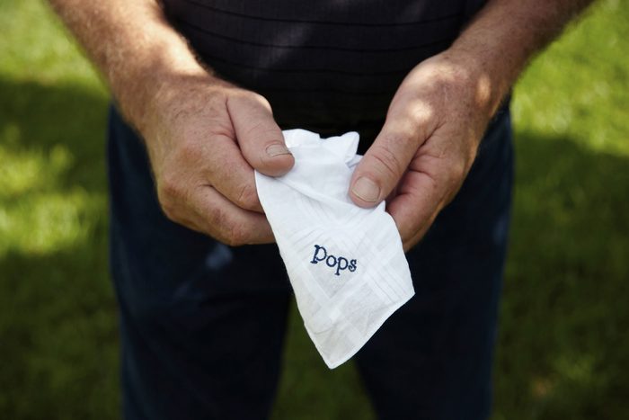 man's hands holding pocket square with "Pops" embroidered