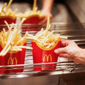 anonymous mcdonalds employee grabs a serving of fries off a metal rack