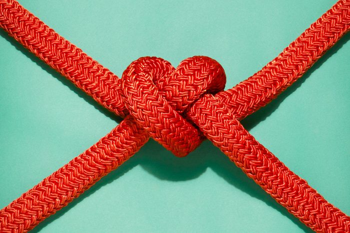 red ropes tied in the shape of a heart on mint green background