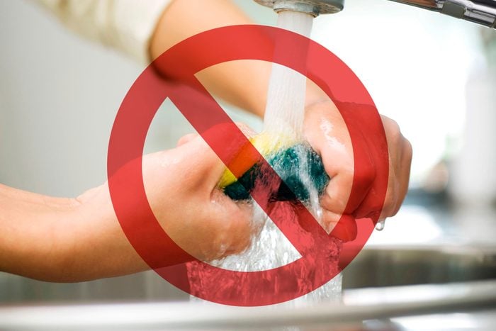 hands wringing out a sponge under running water with a "no" symbol overlay