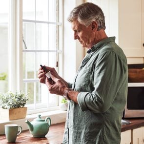 Cropped shot of a relaxed senior man preparing a cup of tea with CBD oil inside of it at home during the day