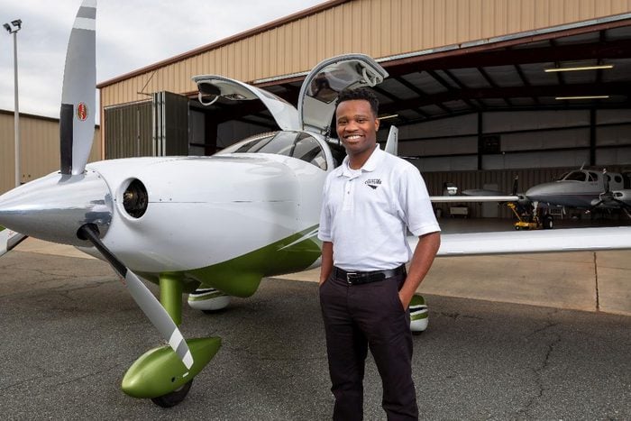 Courtland Savage, a black pilot, standing in front of a small propellor plane