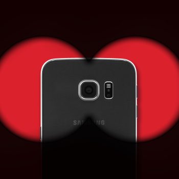 Android phone behind the dark view of binoculars, to represent malware or spyware