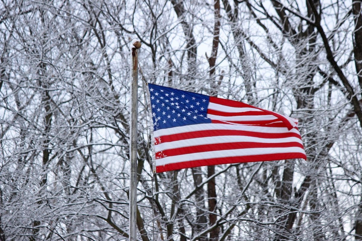 the american flag waves against a wintry background