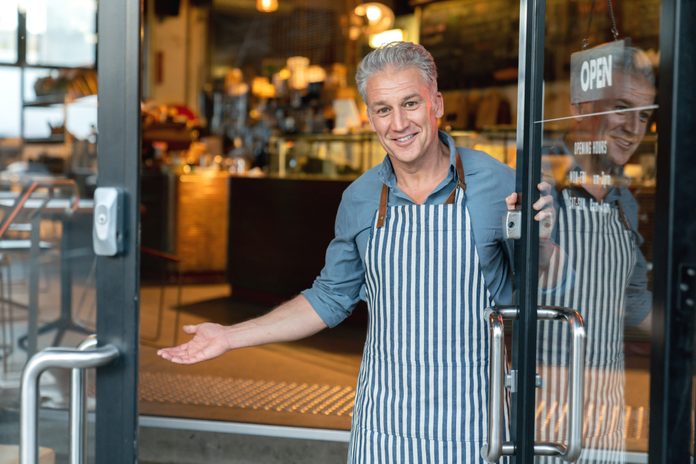 Business owner at the door of a cafe welcoming customers