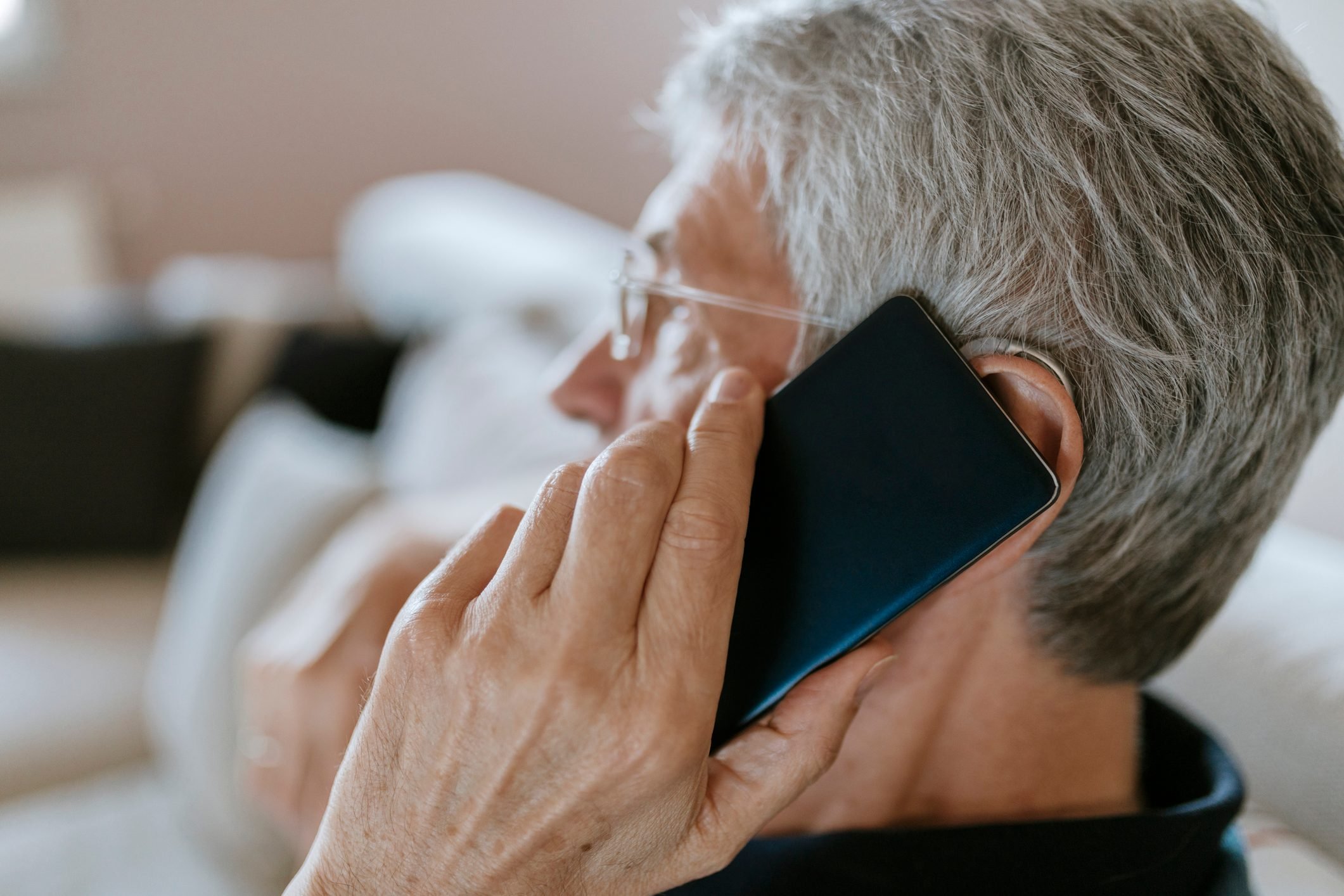 Senior man with hearing aid on cell phone
