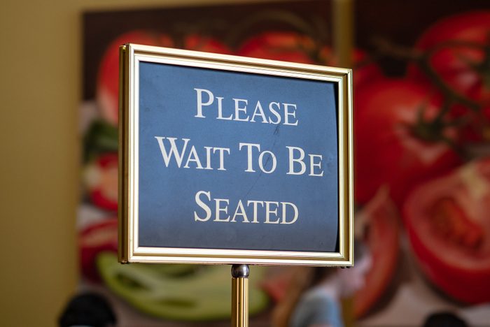 Please wait to be seated sign standing at the front of a restaurant