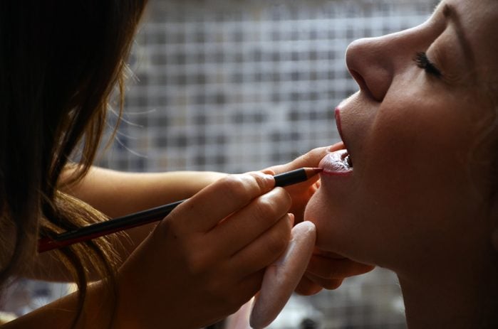Midsection Of Make-Up Artist Applying Lip Liner To Woman In Spa