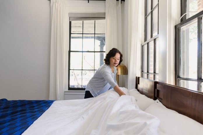 Senior woman concentrates while making her bed