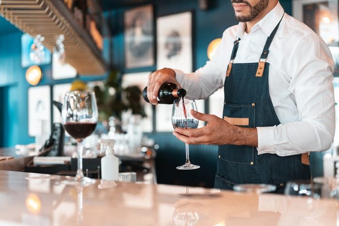 Sommelier serving red wine in luxury hotel bar