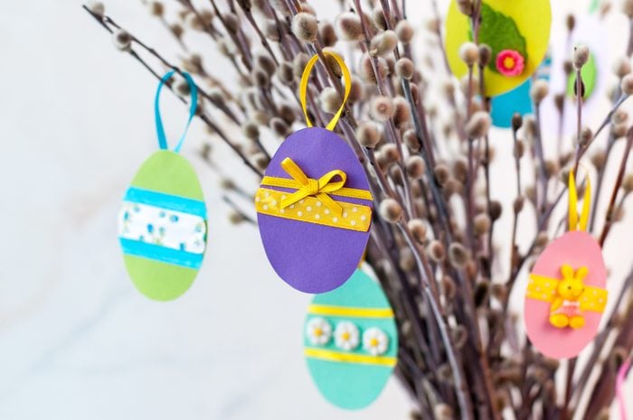 Easter eggs cutted from color paper decorated with ribbon and buttons on willow branches