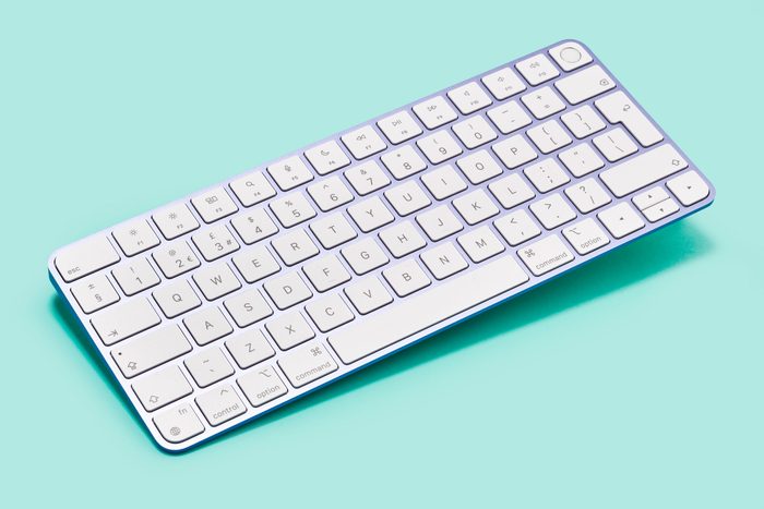 an apple magic keyboard on a bluish teal background