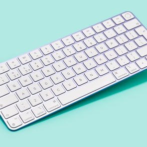 an apple magic keyboard on a bluish teal background