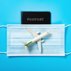 airplane model above a medical mask and a passport