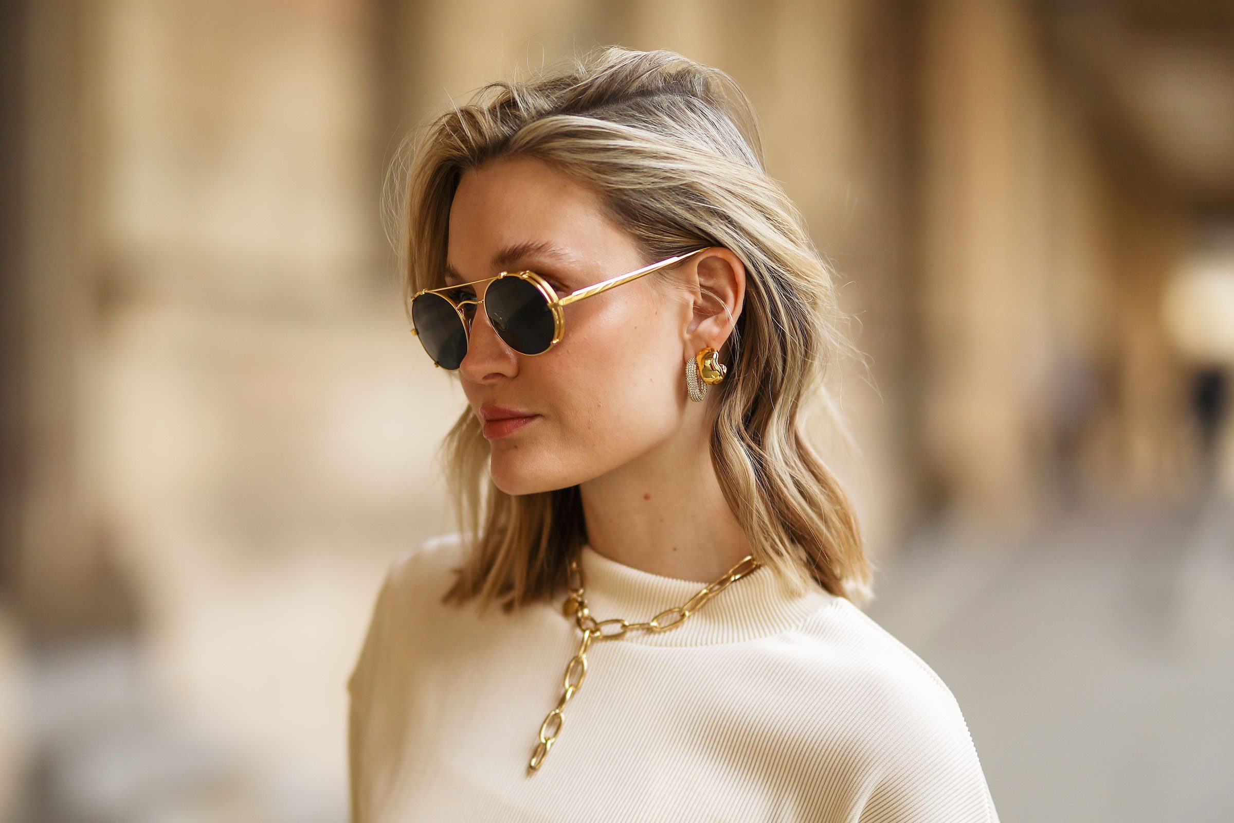woman wearing gold earrings, necklace and glasses