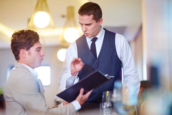 Businessman placing an order with waiter at hotel restaurant