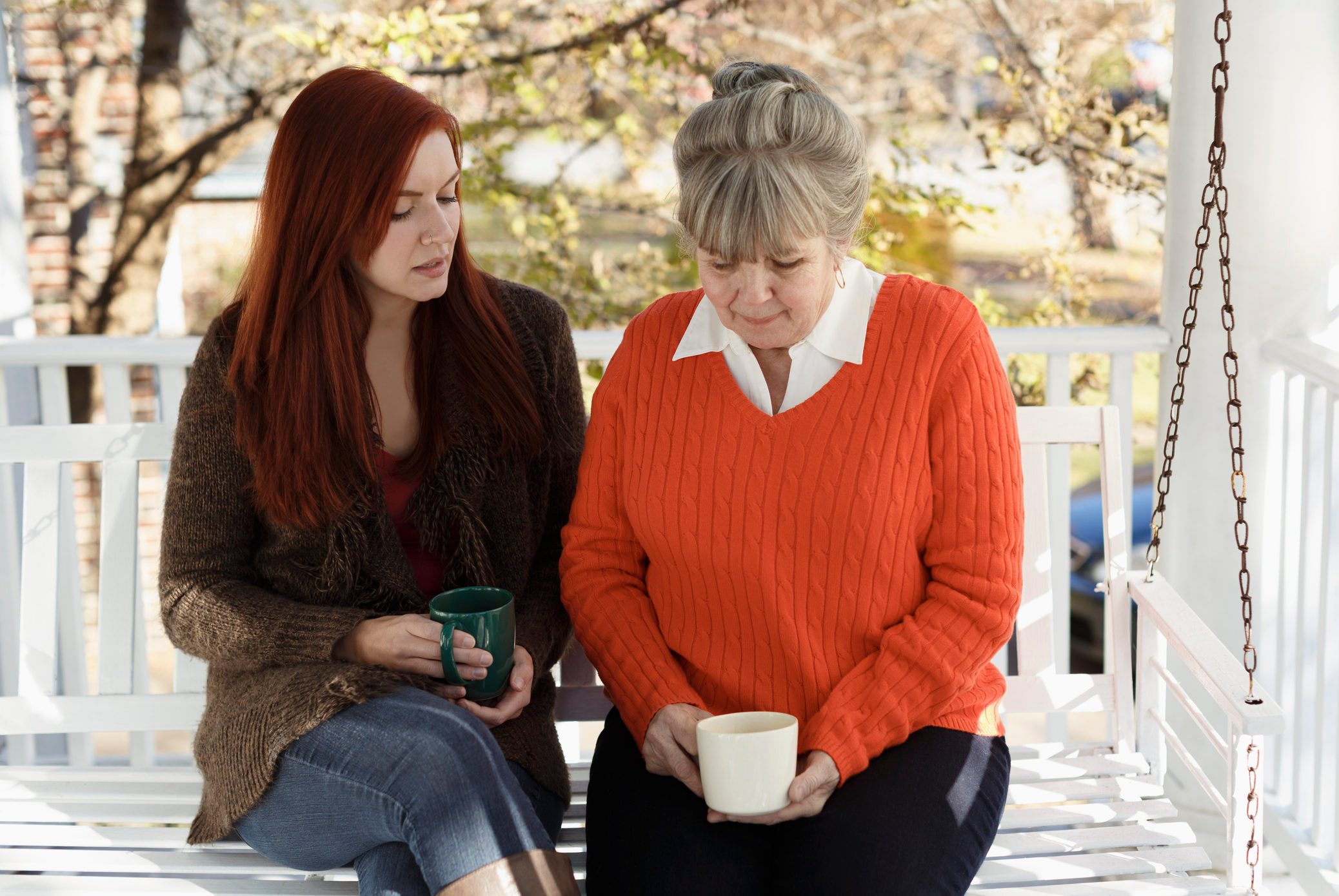 Senior woman and adult daughter having serious discussion on porch