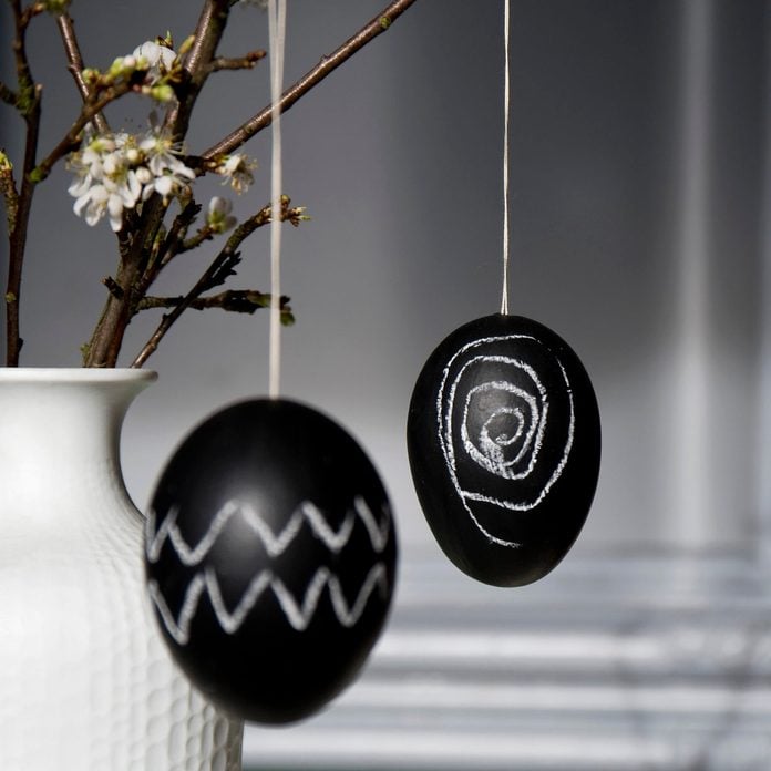 Two Easter eggs painted with blackboard paint and chalk hanging on blossoming twig