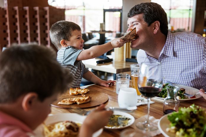 Boy feeding pizza to father in restaurant