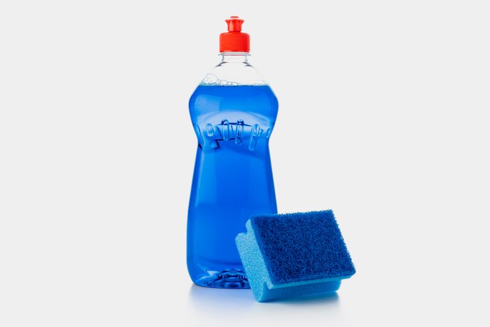 blue dish soap and blue sponge on a grey background