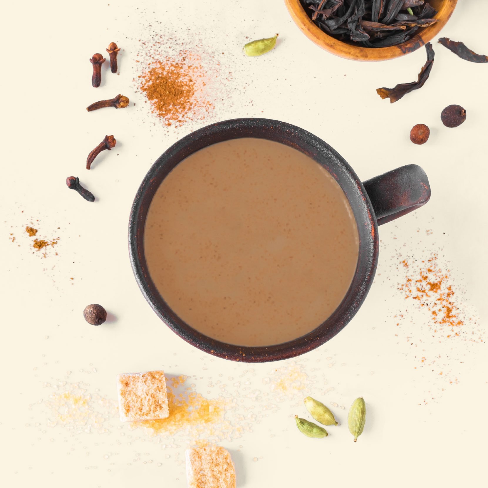 cup of chai tea from overhead with sugar and other ingredients scattered around the mug