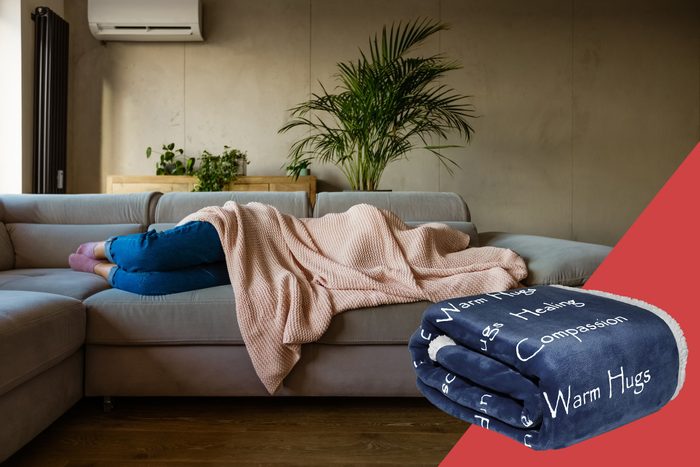 woman lying on couch with blanket over head