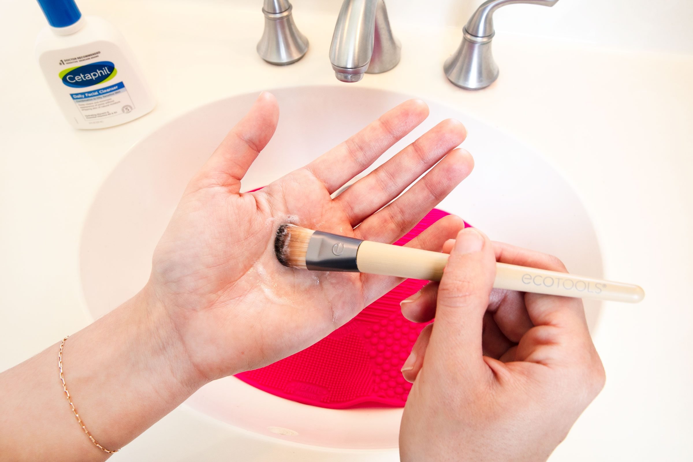 cleaning a make up brush with hands and soap