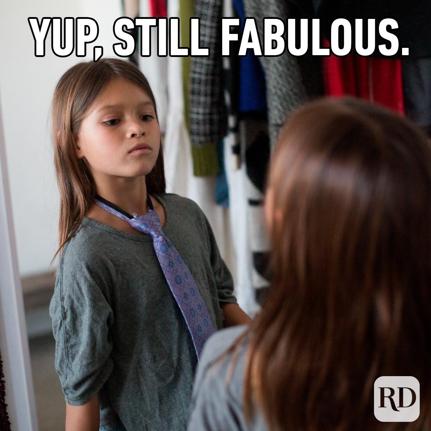Young girl looking at herself in the mirror, wearing a men's necktie. Meme text: Yup, still fabulous.