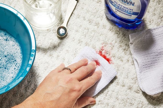 Hand blotting blood stain with mixture of dish soap and water
