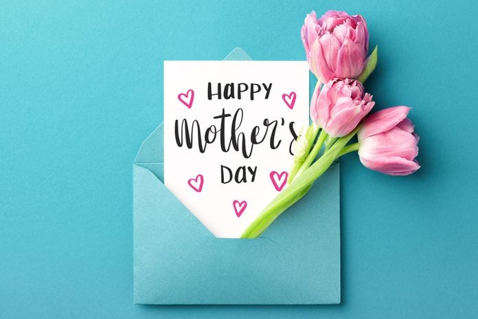 paper and pink flowers sticking out a blue envelope on blue background. card reads "Happy Mother's Day"