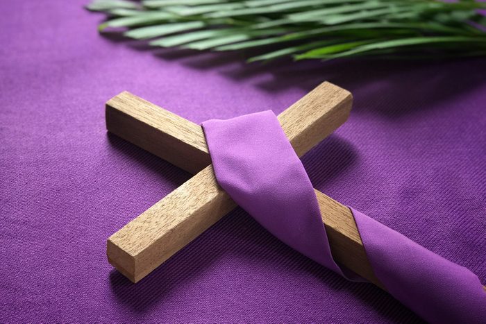 cross and palm leaves on purple background to symbolize Good Friday, Lent Season and Holy Week
